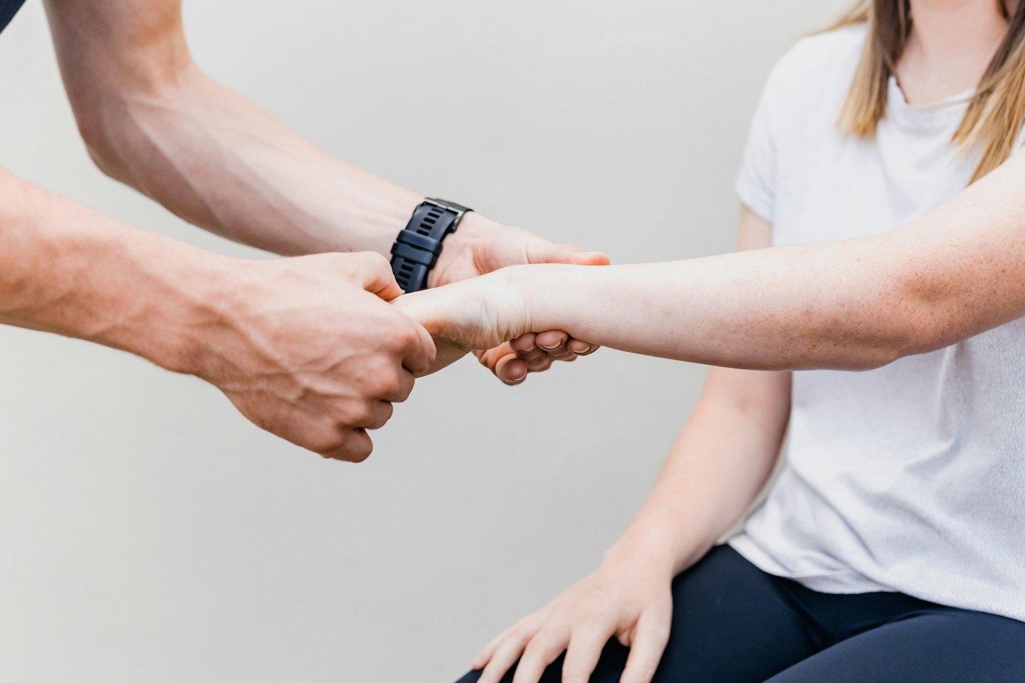 Physiotherapeut untersucht Unterarm und Handgelenk eines Patienten.